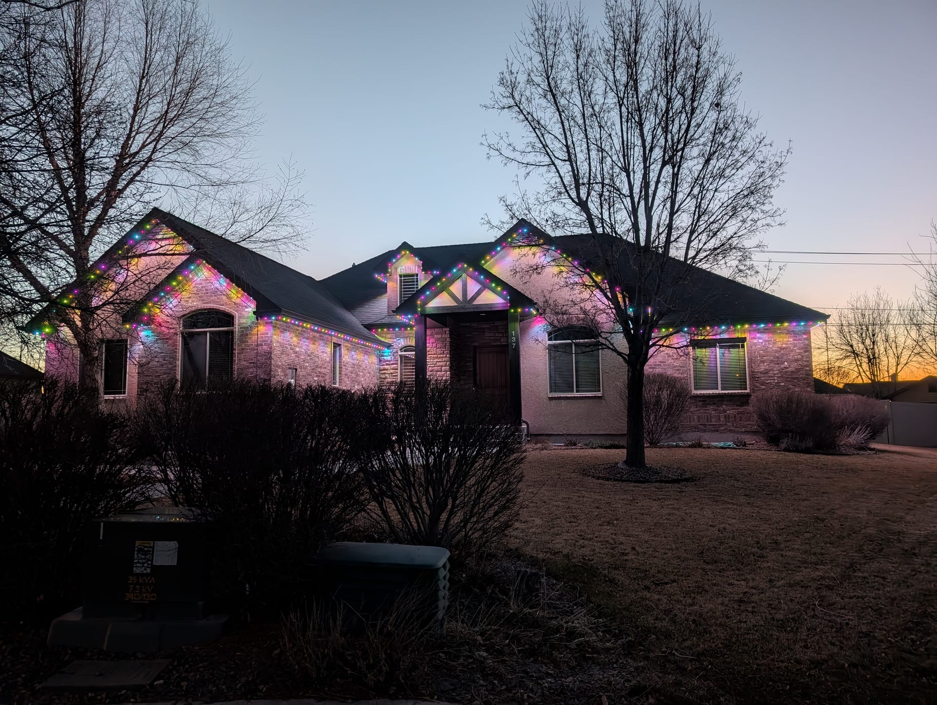Multicolor permanent outdoor LED holiday lighting on home at dusk - smart trim lights