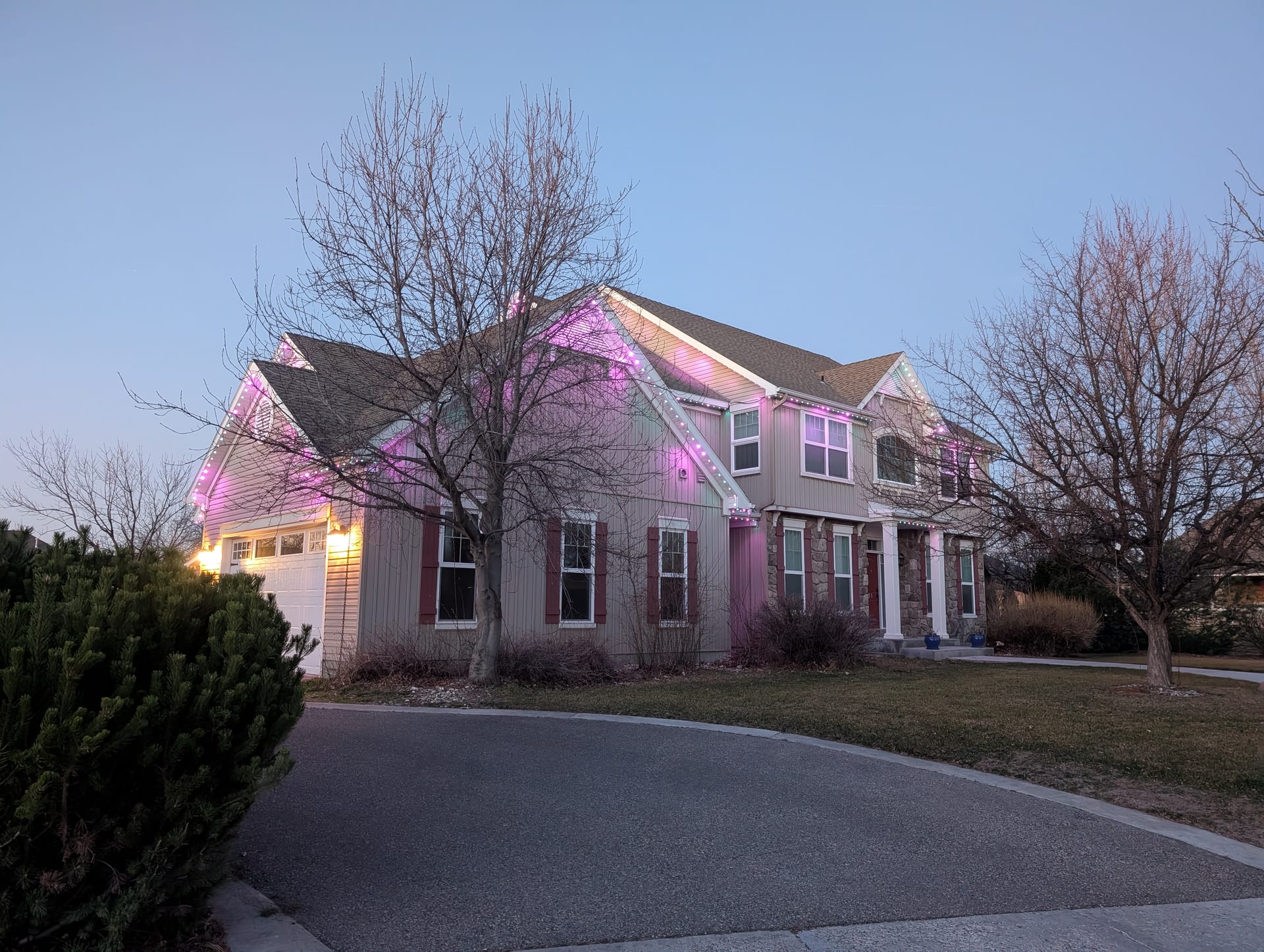 Pink permanent LED trim lights on two-story home roofline - year-round exterior lighting