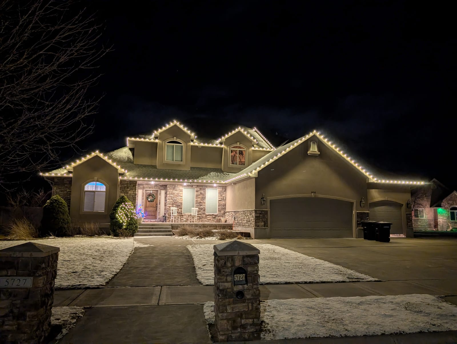Warm white traditional Christmas lights on large luxury home in snow