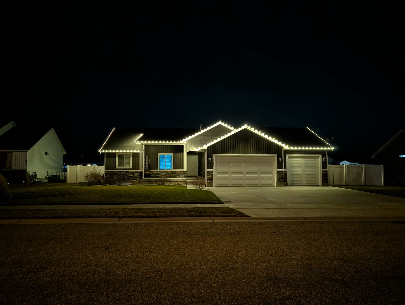 Warm white traditional Christmas lights on modern home roofline