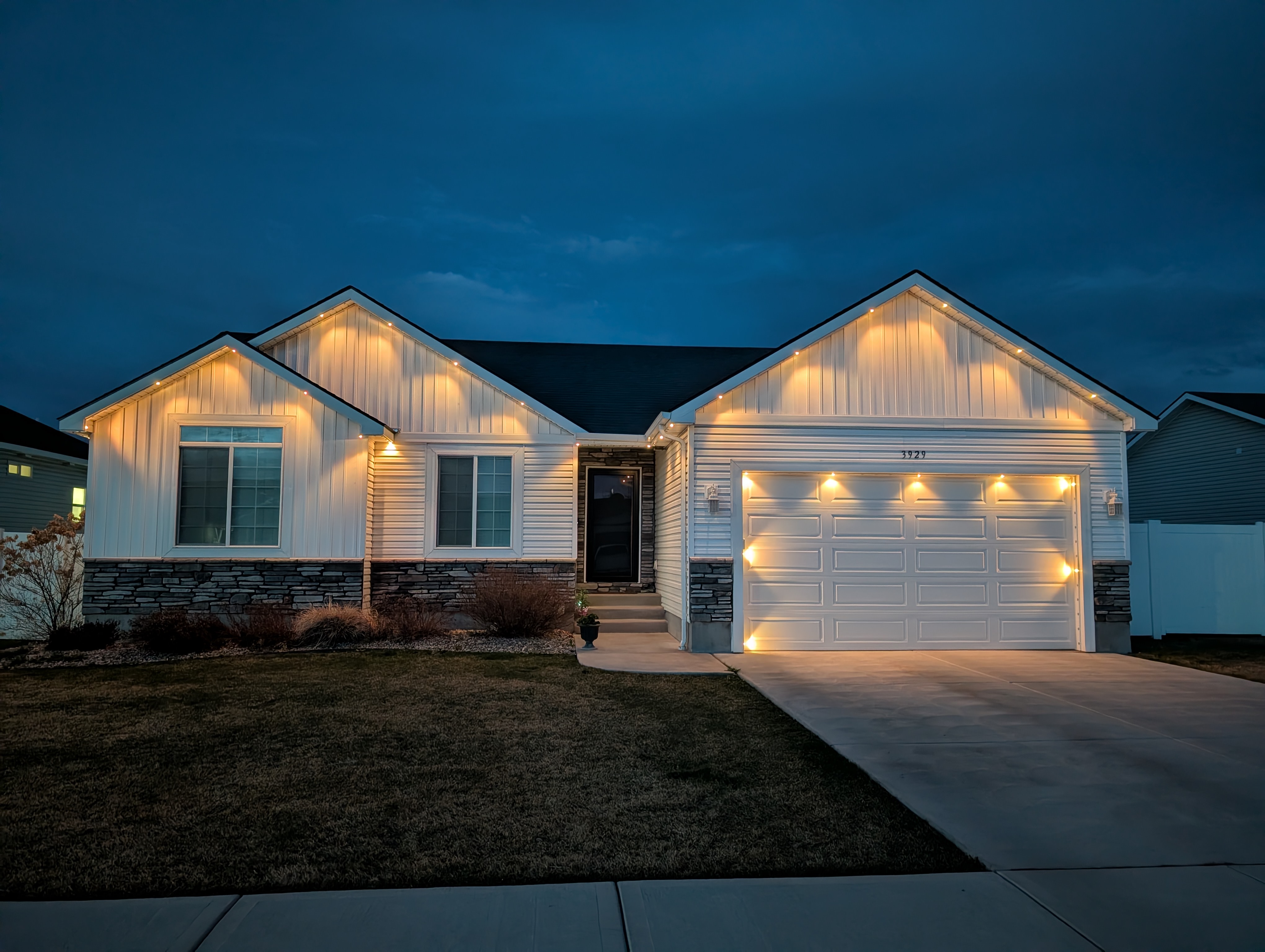 White ranch home with warm white permanent LED roofline lighting at night
